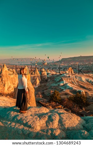 Girl watching the balloons and enjoying amazing view. Cappadocia, Goreme, Turkey.