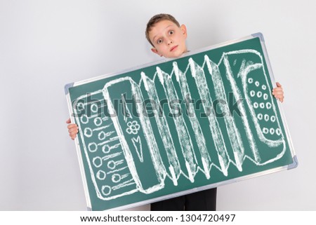 A child who loves to play on the nerves with his funny comic antics. The boy holds a small chalkboard with a drawing of accordion