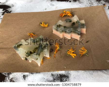 transparent handmade soap in the form of Christmas trees with herbs on a background of rough paper
