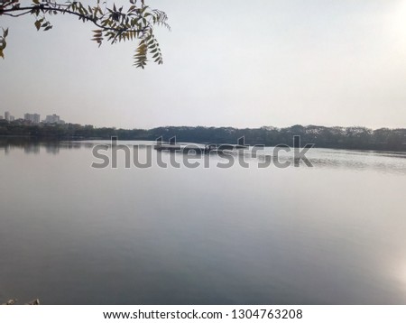 Perfect Picture of lake, where the shun is about to set and fisher is in his boat for fishing. Pic was take from the bank of pond with the angel of a tree which has no leaf. 
