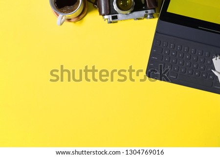 Top view creative yellow  desk with tablet, vintage camera and copy space