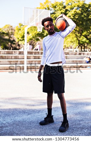 Young athletic black man posinging on court with ball, basketball game player, morning exercises, active healthy lifestyle, hot summer day, streetball. 