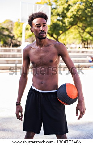 Young athletic black man posinging on court with ball, basketball game player, morning exercises, active healthy lifestyle, hot summer day, streetball. 