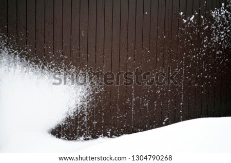 Brown wooden wall covered with snow