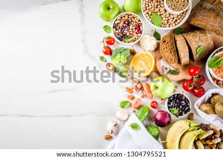 Healthy food. Selection of good carbohydrate sources, high fiber rich food. Low glycemic index diet. Fresh vegetables, fruits, cereals, legumes, nuts, greens. White marble background copy space Royalty-Free Stock Photo #1304795521