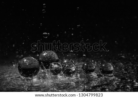 Black white glass balls on a black background in the rain with large drops