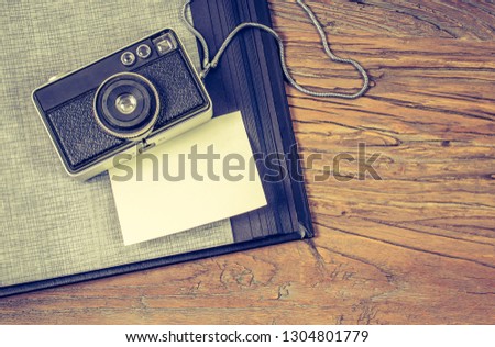Travel memories concept: Flat lay of old camera and photo album with white blank paper for message.