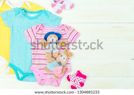 Set of clothing and items for a newborn baby placed on white wooden board.