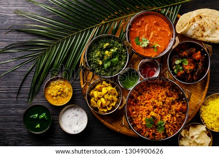 Indian food Curry butter chicken, Palak Paneer, Chiken Tikka, Biryani, Vegetable Curry, Papad, Dal, Palak Sabji, Jira Alu, Rice with Saffron on dark background Royalty-Free Stock Photo #1304900626