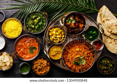 Indian food Curry butter chicken, Palak Paneer, Chiken Tikka, Biryani, Vegetable Curry, Papad, Dal, Palak Sabji, Jira Alu, Rice with Saffron on dark background Royalty-Free Stock Photo #1304900848