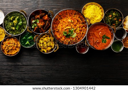 Indian food Curry butter chicken, Palak Paneer, Chiken Tikka, Biryani, Vegetable Curry, Papad, Dal, Palak Sabji, Jira Alu, Rice with Saffron on dark background copy space Royalty-Free Stock Photo #1304901442