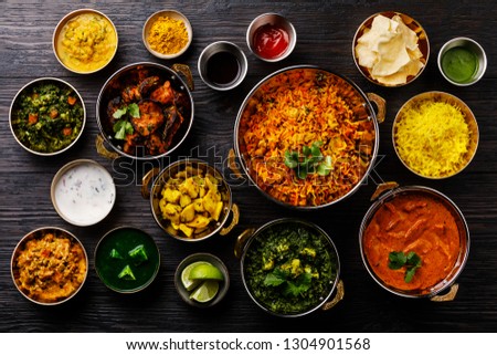 Indian food Curry butter chicken, Palak Paneer, Chiken Tikka, Biryani, Vegetable Curry, Papad, Dal, Palak Sabji, Jira Alu, Rice with Saffron on dark background Royalty-Free Stock Photo #1304901568