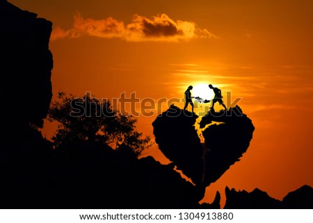 Couple on the broken heart shape rock on the mountain with red sky sunset.Silhouette Valentine background concept.