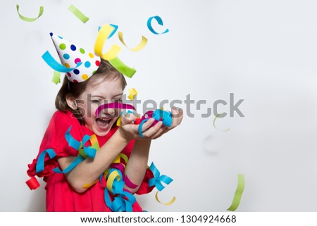 Birthday, New year's carnival. A child on a white background celebrates a bright event, wears a red dress and a cap. Sparkling confetti, having fun, dancing-image
