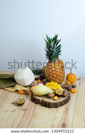 Various kinds of tropical fruits in plates on the table. Mango, tamarind, kumquat, pitahaya, pineapple, granadilla, lychee, passion fruit and young coconut. Space for text.