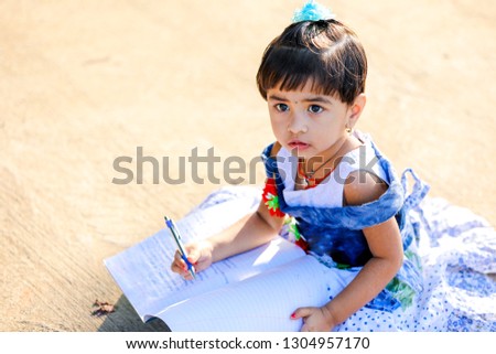 Indian Little Girl child writing on note book , studying 