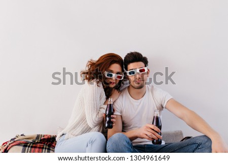 Couple in 3d glasses watching movie. Friends drinking soda on sofa.