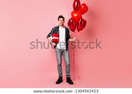Full length view of man with air balloons standing on pink background, valentine's day concept.