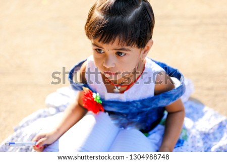Indian Little Girl child writing on note book , studying 