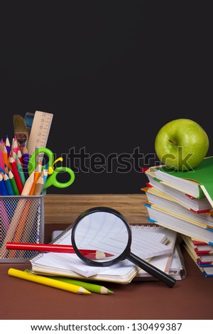 green apple,  board, books, pencils, opened empty notebook lie on school desk