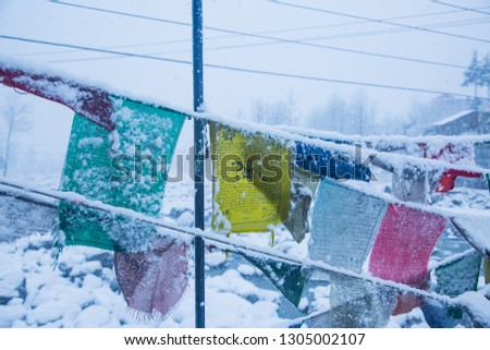 Colorful Tibetan prayer flags covered in snow, himalayan mountains in winters, Nepal