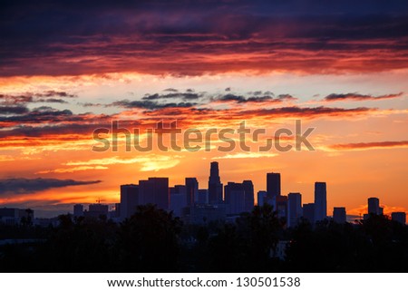 Fiery sunrise clouds over downtown Los Angeles city skyline.