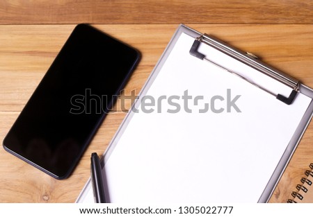 Working place on wooden table. Office desk table with eye glasses notebook, pen ,clips,and smartphone. Top view with copy space, flat lay