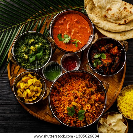 Indian food Curry butter chicken, Palak Paneer, Chiken Tikka, Biryani, Vegetable Curry, Papad, Dal, Palak Sabji, Jira Alu, Rice with Saffron on dark background Royalty-Free Stock Photo #1305026884