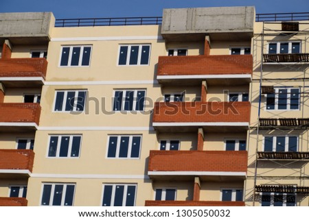 The wall of a high-rise brick house, red balconies and yellow walls.