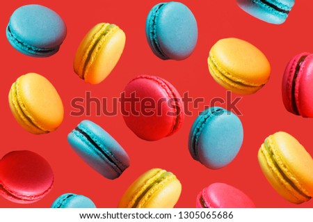 Different types of macaroons in motion falling on a pink background. Turquoise, orange sweet French pastries, closeup