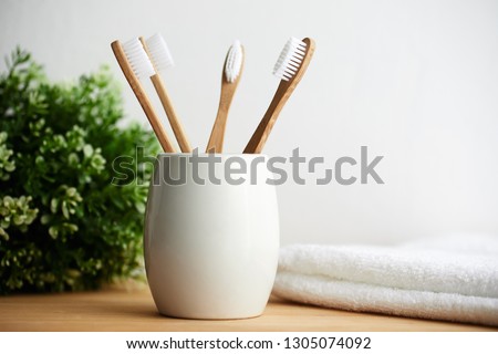 Four bamboo toothbrushes in a glass with copy space on a wooden background Royalty-Free Stock Photo #1305074092
