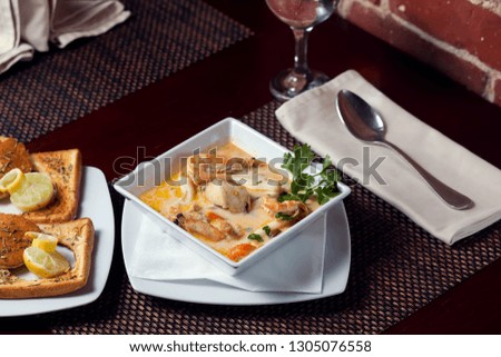 Seafood cream soup with toasts in white plate on the table.
