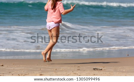 little girl running along the sea on a sandy beach