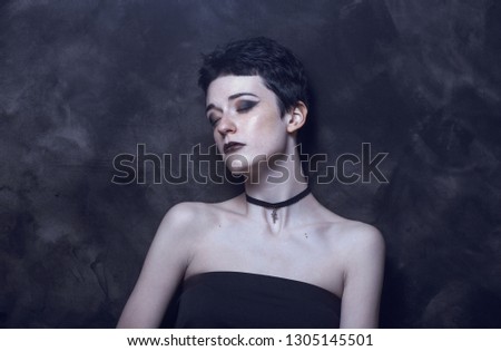 A young girl with androgynous appearance and dark gothic makeup.