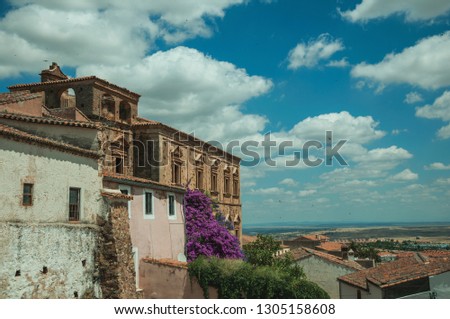 Old buildings and flowering trees with a countryside landscape in the background at Caceres. A cute and charming town with a fully preserved medieval city center in western Spain.