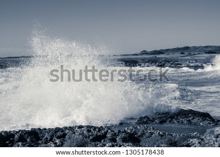 Spray created by waves of the sea that hurl themselves against the rocky coast of Salento, monochrome interpretation of the shot.
