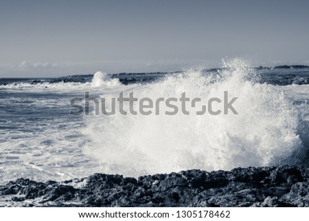 Spray created by waves of the sea that hurl themselves against the rocky coast of Salento, monochrome interpretation of the shot.
