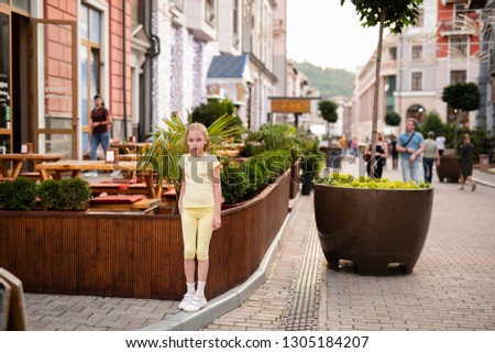 Portrait of blonde girl 10 years old playing among beautiful old houses.
