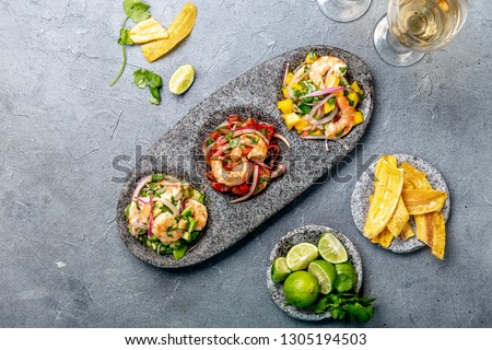 CEVICHE. Three colorful shrimps ceviche with mango, avocado and tomatoes. Latin American Mexican Peruvian Ecuadorian food. Served with white wine and banana chips Royalty-Free Stock Photo #1305194503