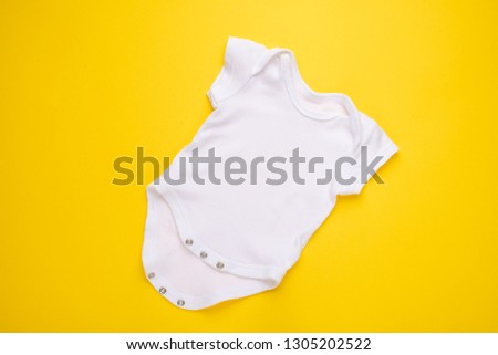 mockup Flat Lay white baby shirt on a yellow background. Layout for the design and placement of logos, advertising, children's party baby shower, children's birthday