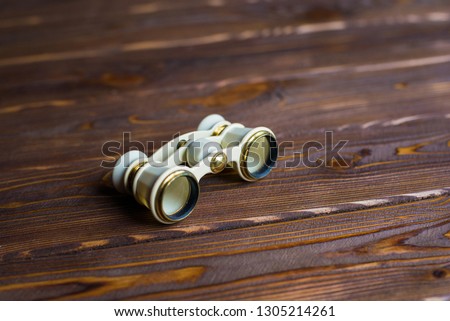 Ivory opera glasses dark wooden background. Theatrical binoculars.