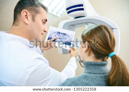 The doctor shows the patient an x-ray image. Computer diagnostics. dental tomography Royalty-Free Stock Photo #1305222358
