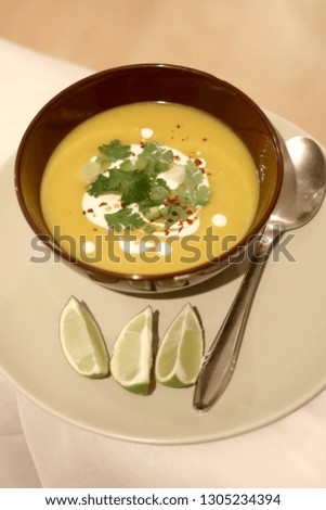 Bowl of pumpkin and potato soup, served with cream, parsley and lemon. Selective focus.