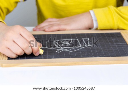 Child drawing house on a blackboard. Real estate concept