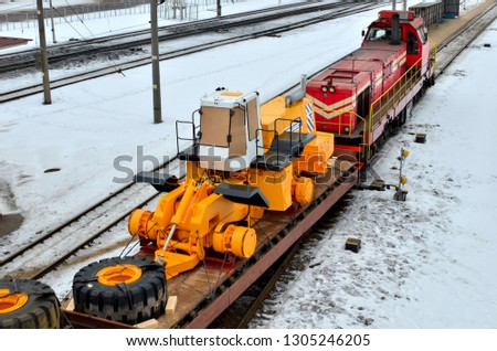 The yellow and front loader disassembled into parts is loaded onto a cargo railway platform. Logistics of delivery of the truck, transportation of heavy heavy machinery