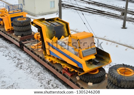 Transportation of heavy mining equipment by rail. Disassembled yellow mining truck loaded onto a cargo railway platform. Multimodal logistics of transportation of oversized cargo