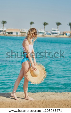 Girl, model in a swimsuit on the beach in Hurghada. The shore of the red sea with panama in your hands