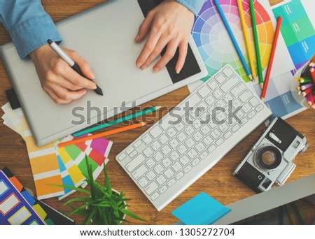 Young cute Graphic designer using graphics tablet to do his work at desk view from above