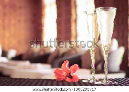 Two glasses of champagne with red flower in a spa lounge. Spa time concept. Spa lounge area. Valentines background. Romance concept. Horizontal. Glitch effect, colorful disruptive