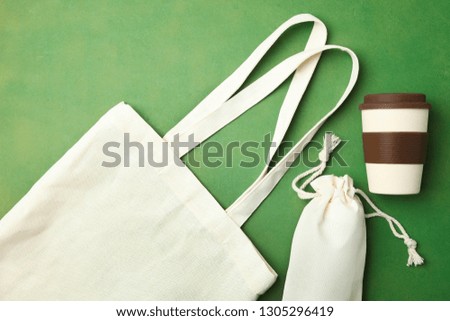 Eco bag and reusable bamboo cup on green background. Concept ecology conservation. Flat lay, copy space. Environmentally friendly materials.